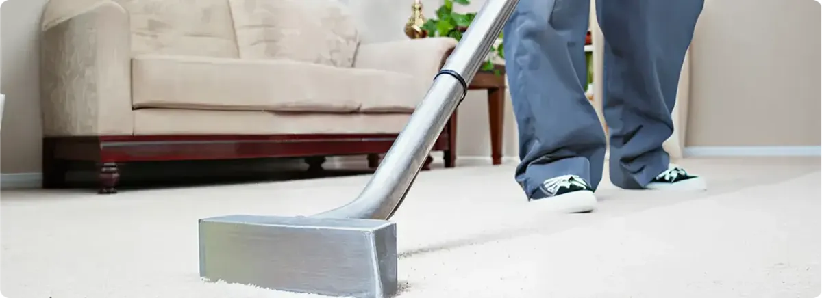 Carpet cleaning technician using a hot-water extraction wand on a light-colored carpet in a living room, Myrtle Beach, SC.